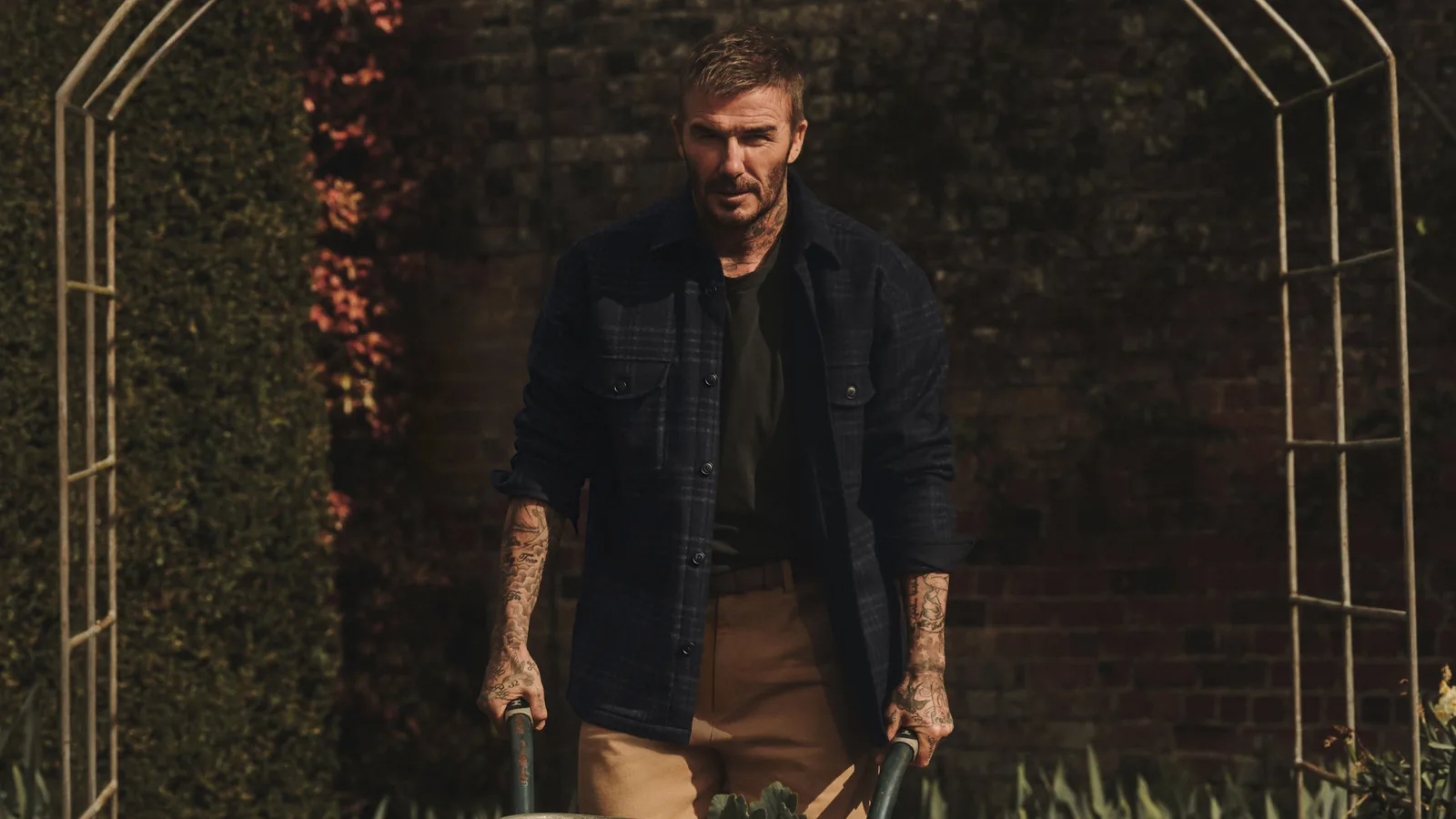 BOSS by Beckham de HUGO BOSS: David Beckham con sobrecamisa de cuadros y una carretilla en el jardín