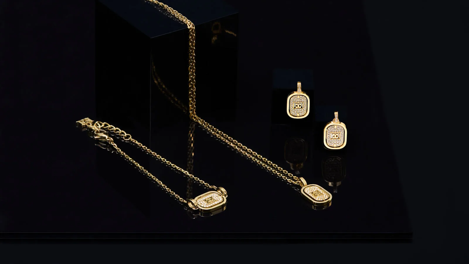 Joyas de ESCADA: cadenas y colgantes dorados con el logotipo sobre fondo oscuro